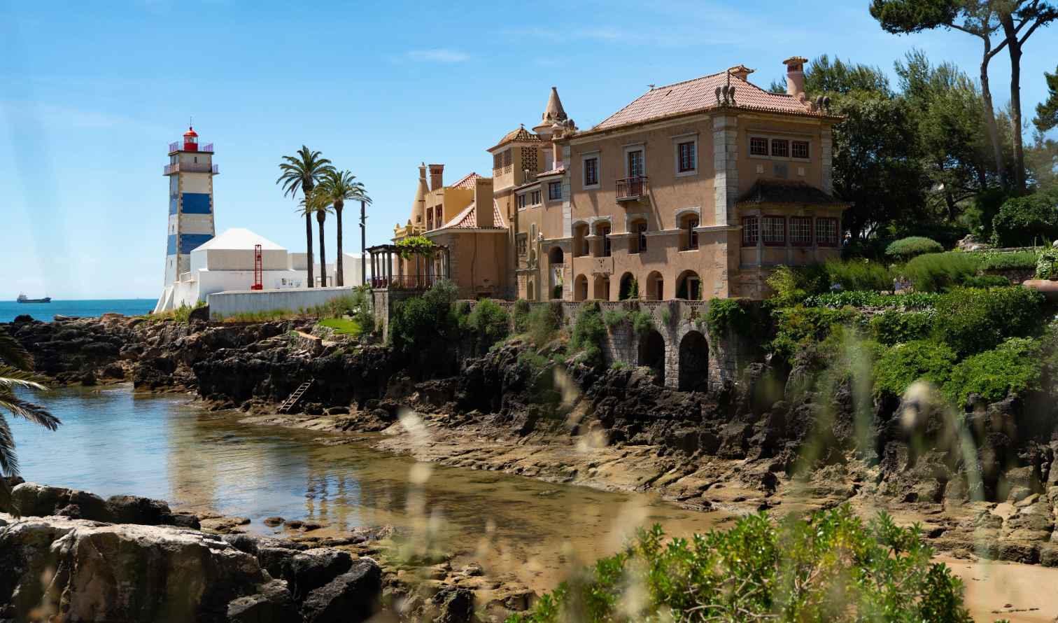 Santa Marta Lighthouse near oceanfront building in Cascais, Portugal.