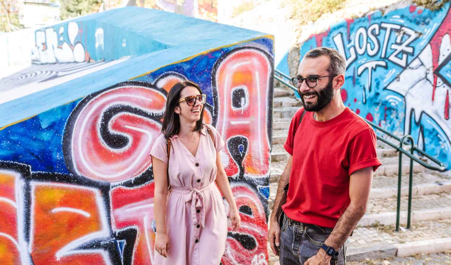 Two people standing near colorful graffiti in Bairro Alto, Lisbon.