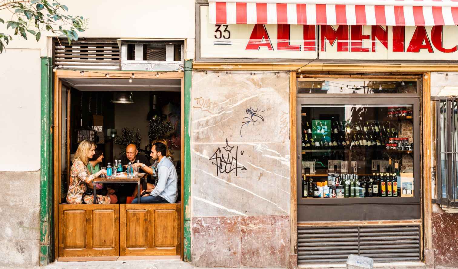 Red-and-white striped awning over a storefront labeled Alimentación in Madrid