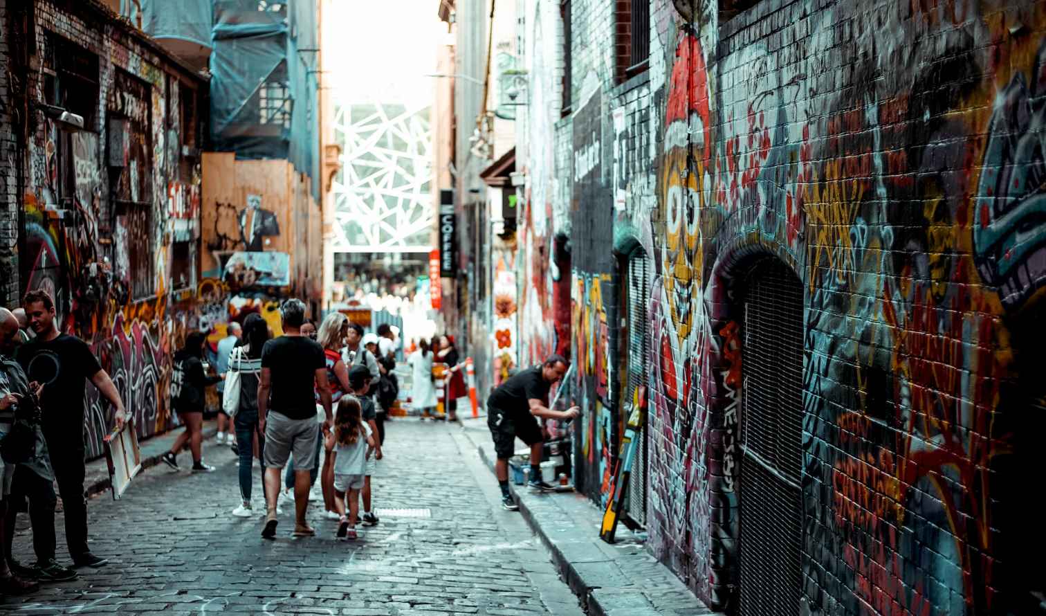 People walking through Hosier Lane, Melbourne, covered in graffiti art.
