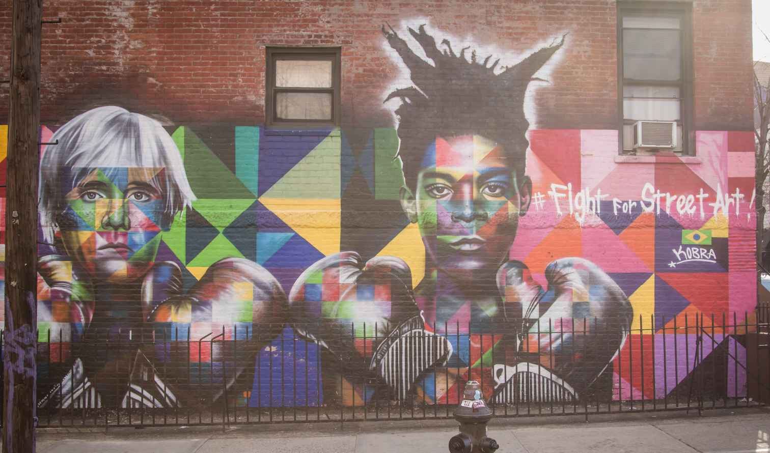 Street mural of two artists on a brick wall near Orchard Street, New York.