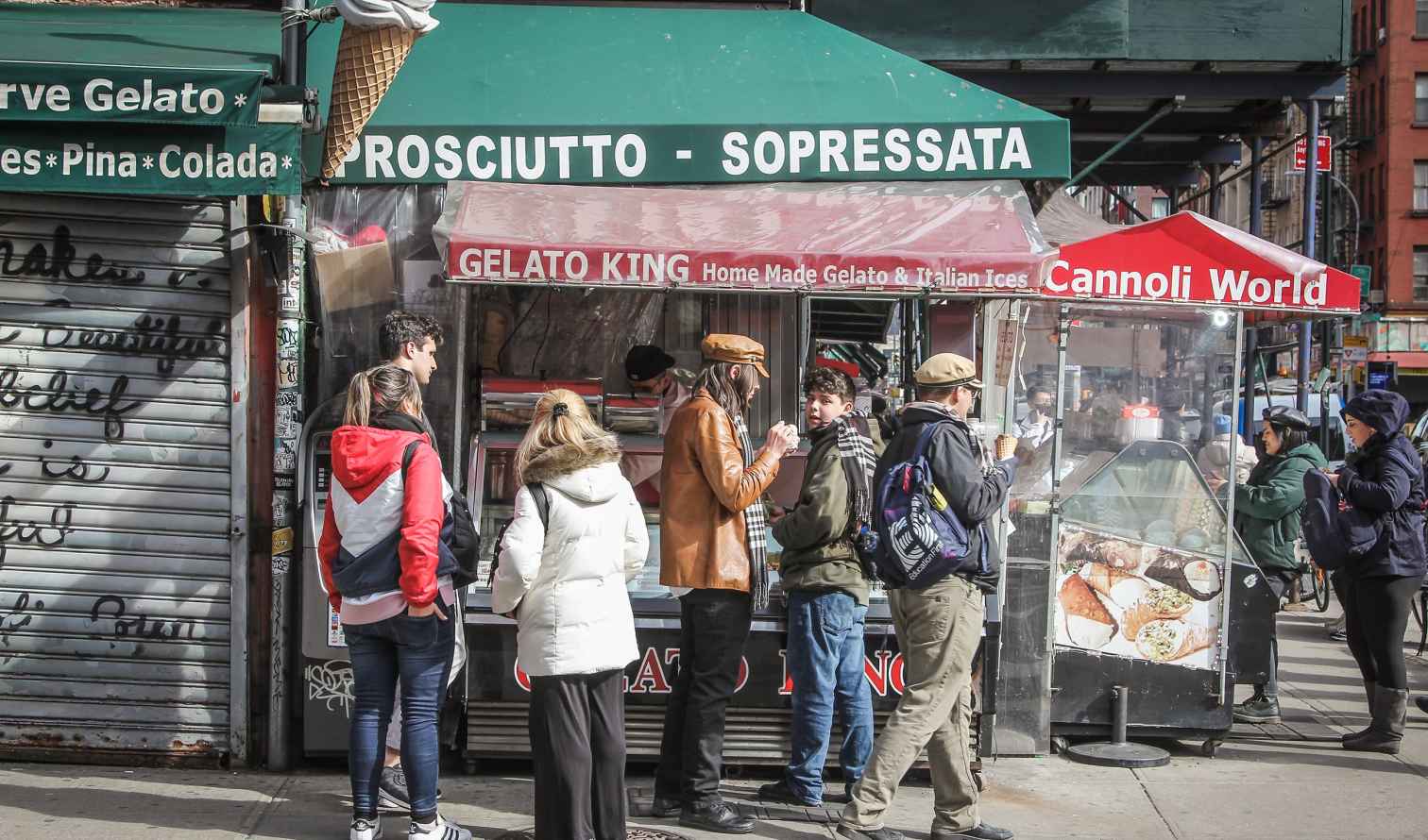People standing outside a Gelato King stand on a corner in Little Italy, New York.