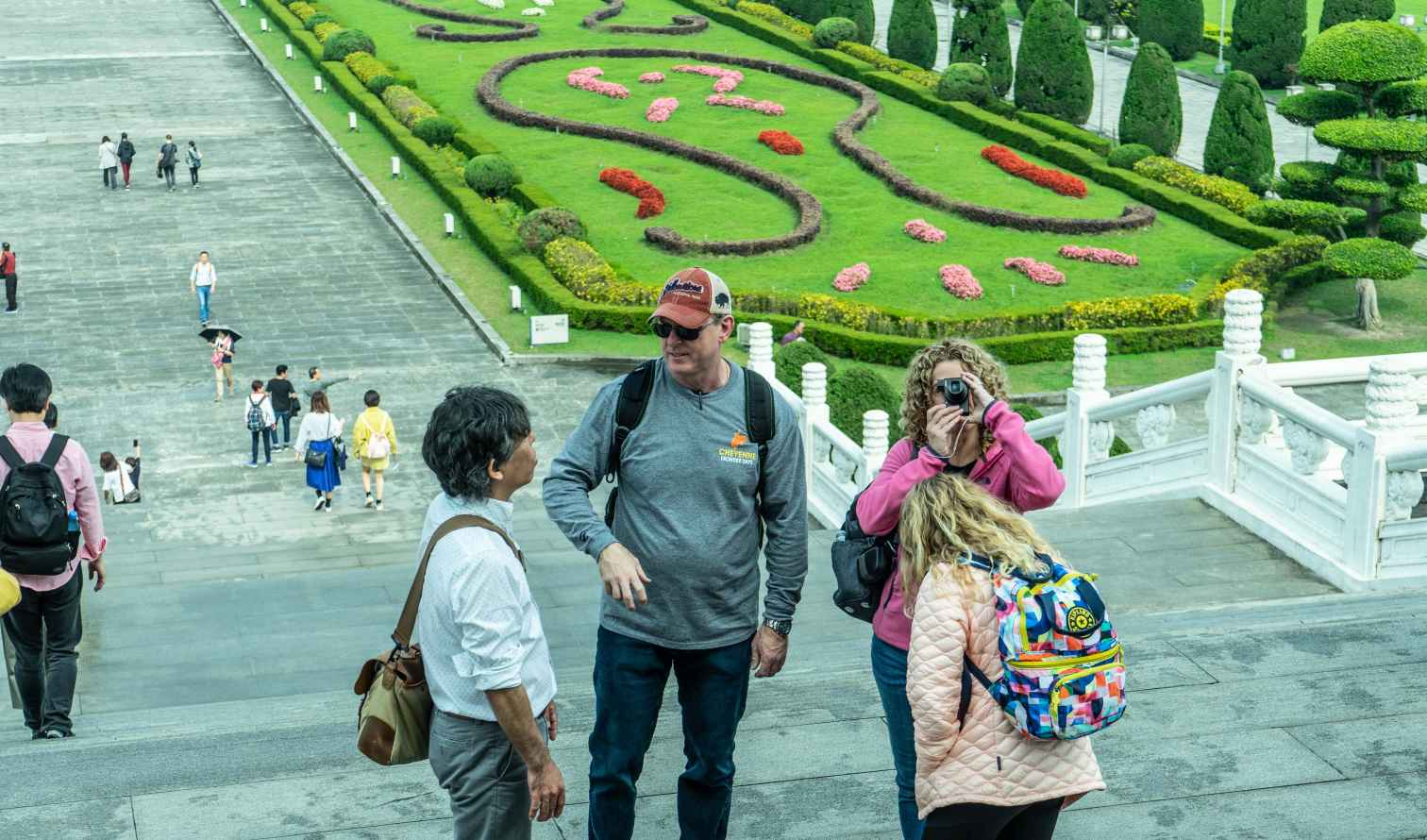 Tourists on steps at Chiang Kai-Shek Memorial Hall, Taipei, with manicured gardens nearby.