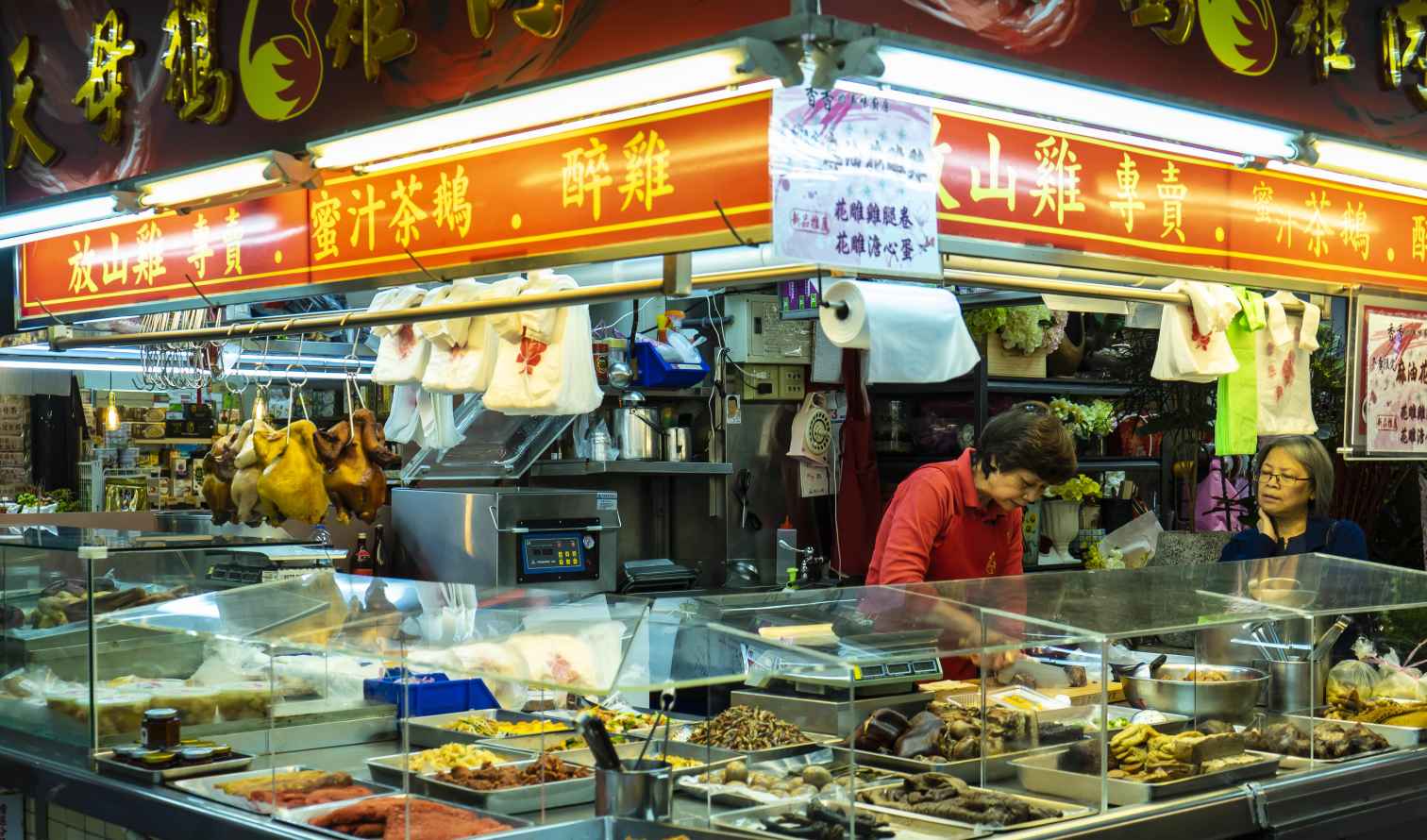 Two people are working at a food stall in the Taipei market.