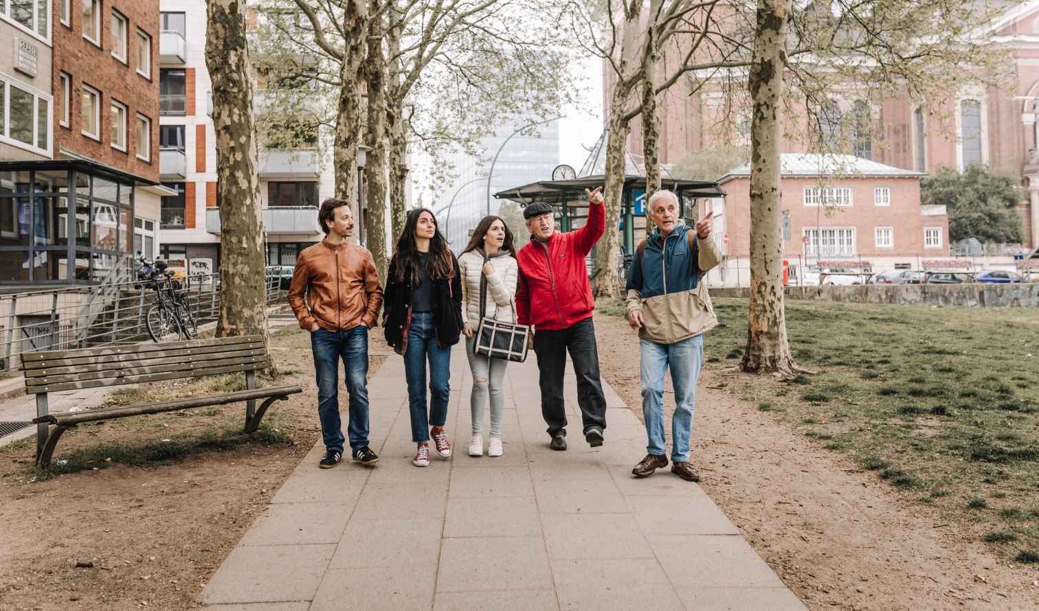Group of five people walking on a sidewalk near trees in Hamburg.