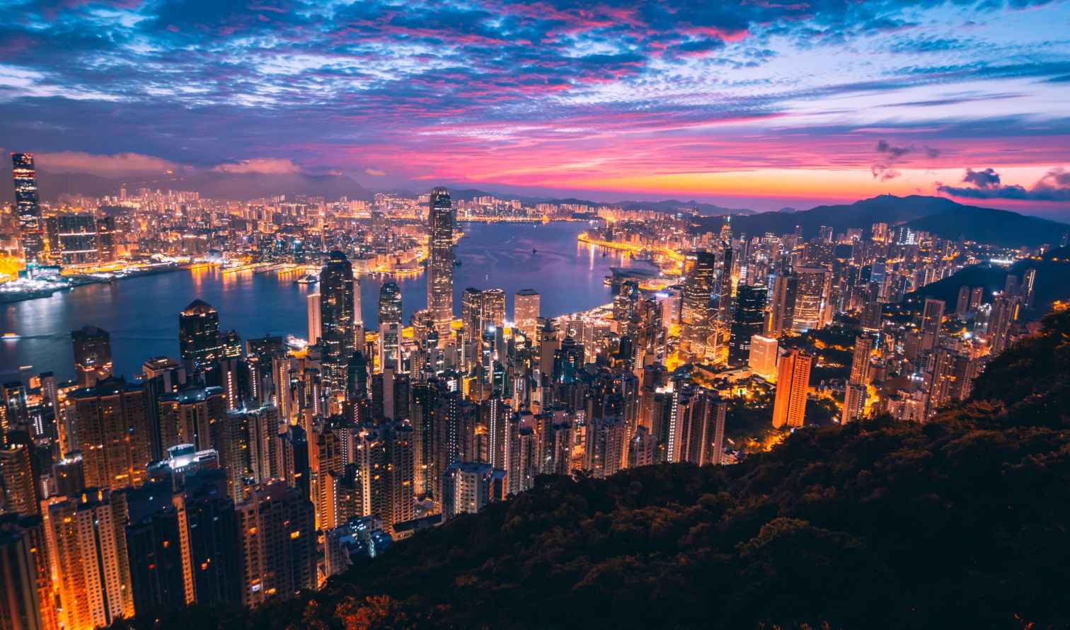 Aerial view of Hong Kong skyline and Victoria Harbour at sunset.