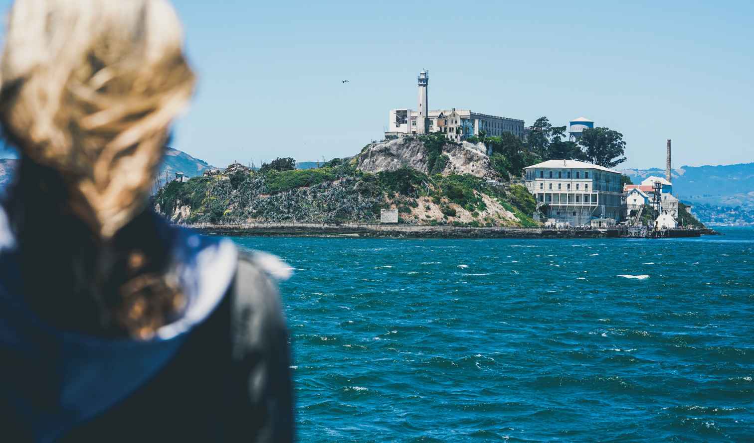A person looks at Alcatraz Island from a distance across the water.