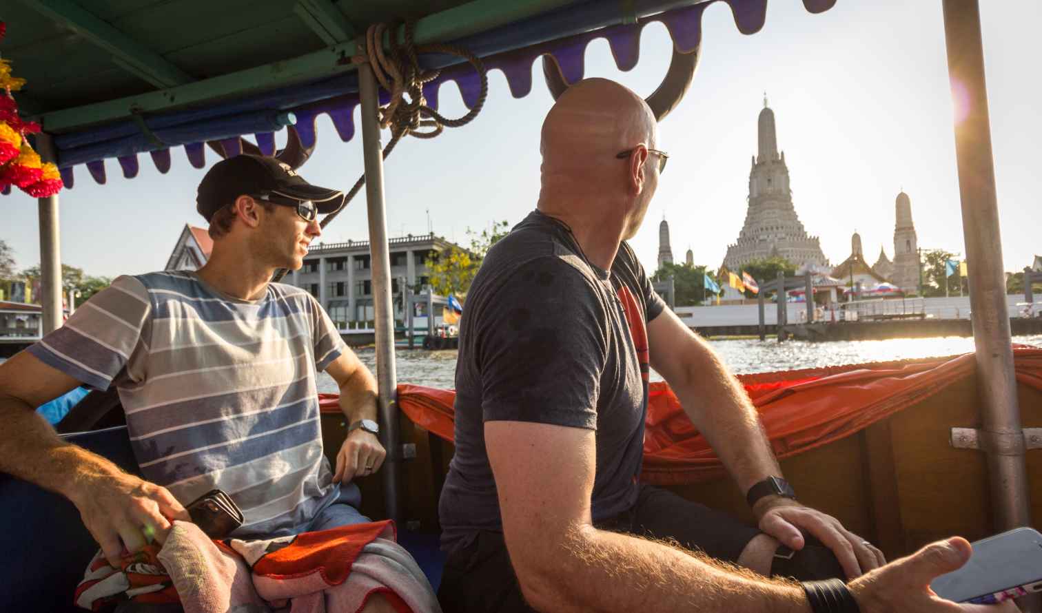 Two people on a boat near Wat Arun temple, Bangkok.