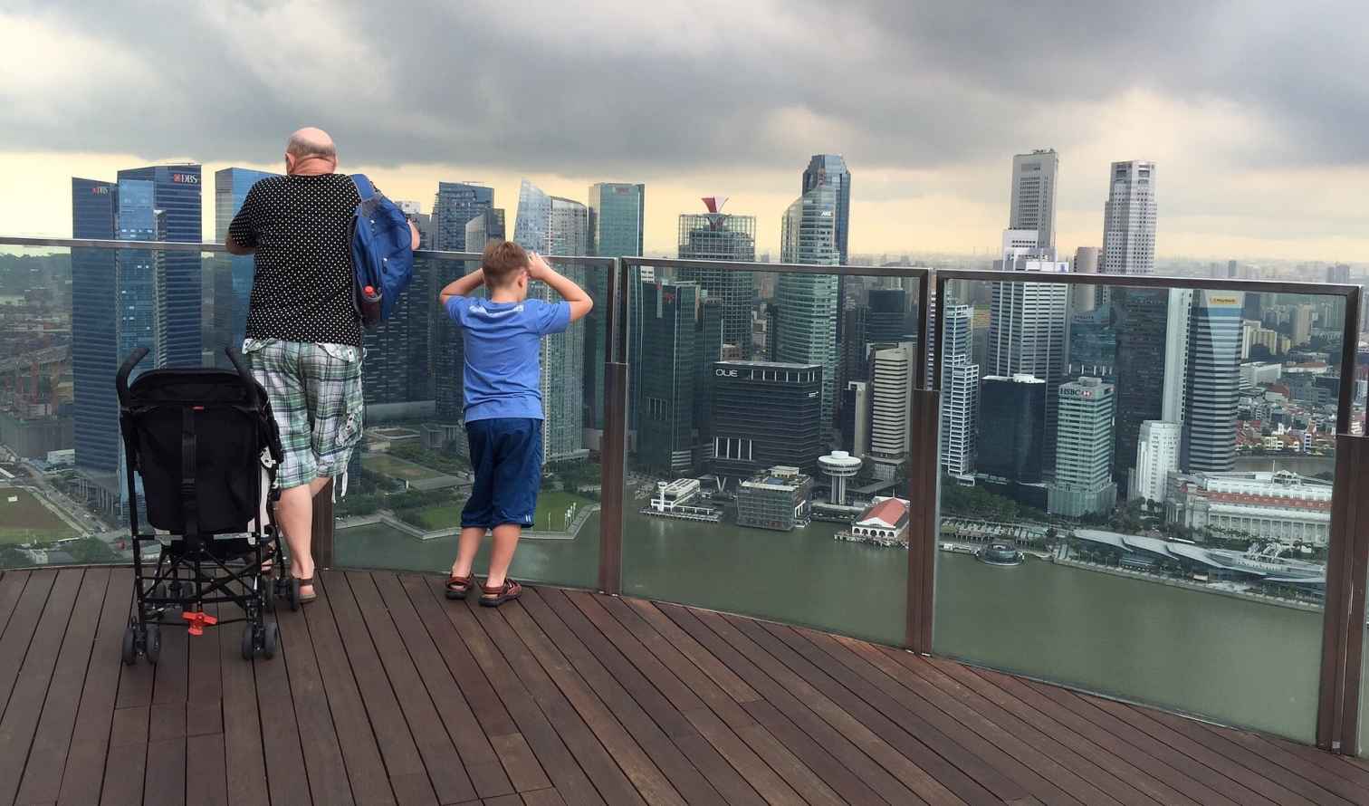 Father and son viewing Singapore skyline from Marina Bay Sands observation deck.