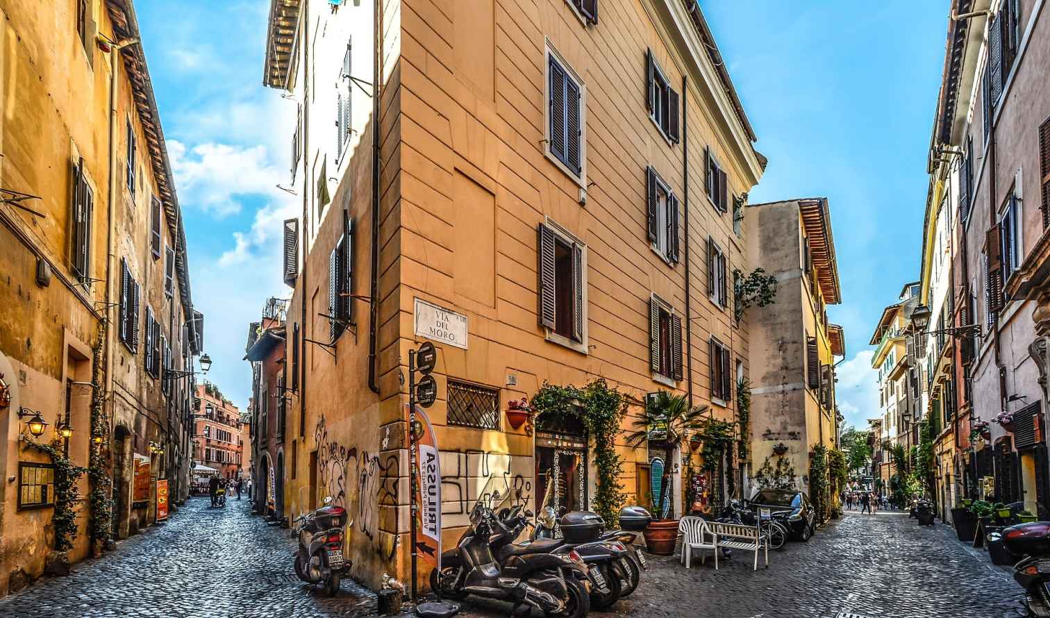 Cobblestone street view at Via del Moro, Rome, with parked scooters.