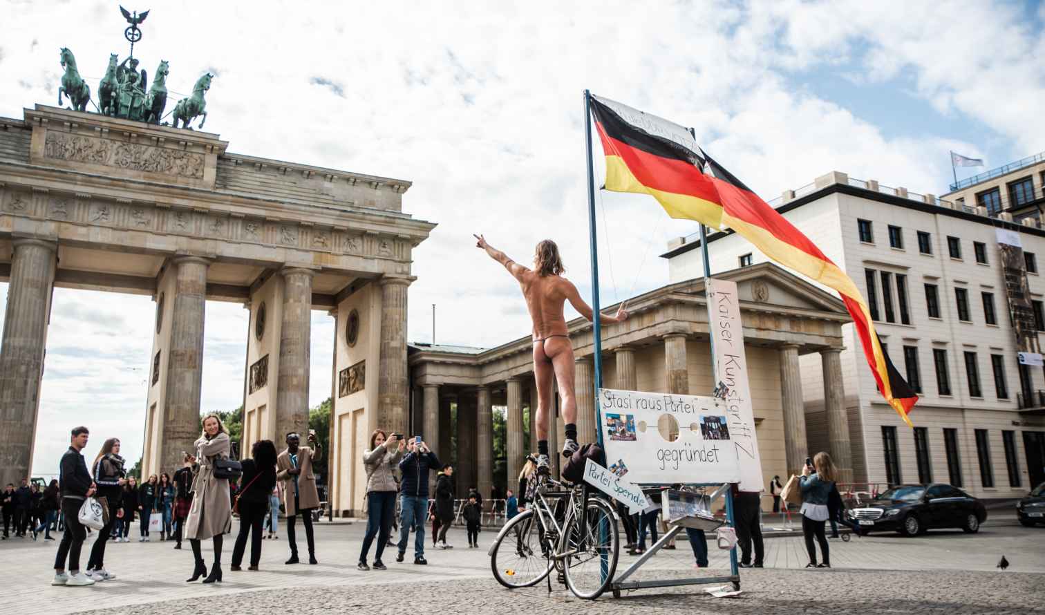 People gathered near the Brandenburg Gate in Berlin on a sunny day.