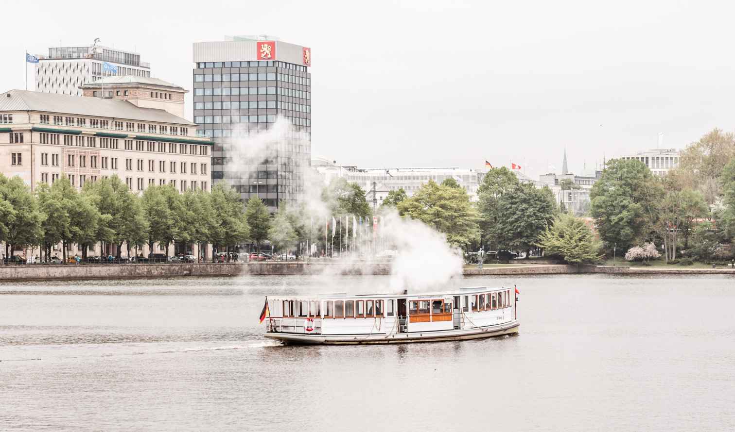 Tour boat sailing on Binnenalster lake in Hamburg, Germany, with buildings in background.