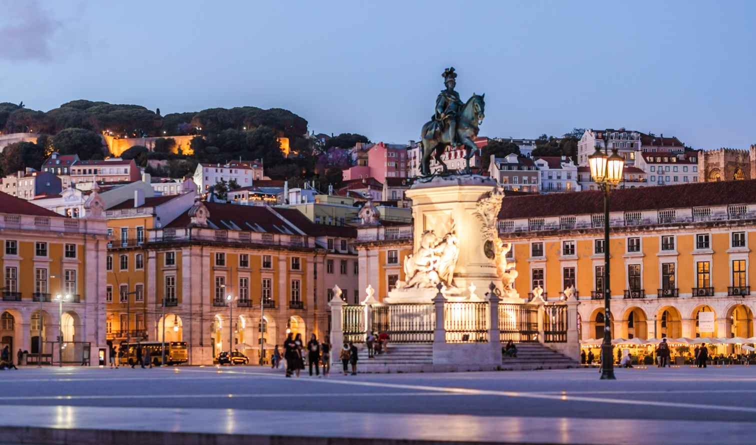 Equestrian statue in Praça do Comércio, Lisbon with nearby hills in view.