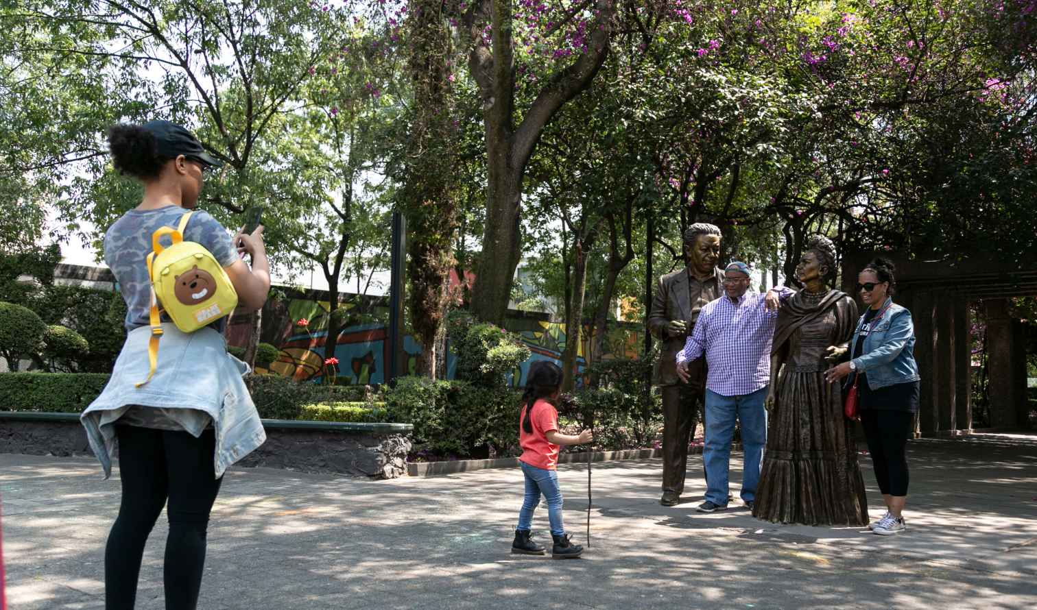 People posing with statues in a park, likely Mexico City.