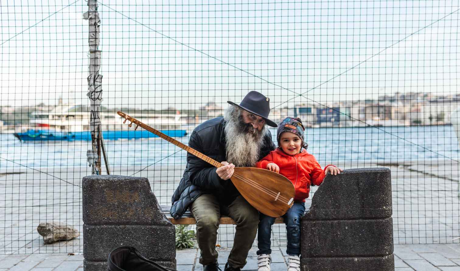 A man and child sit on a bench near Istanbul's waterfront.