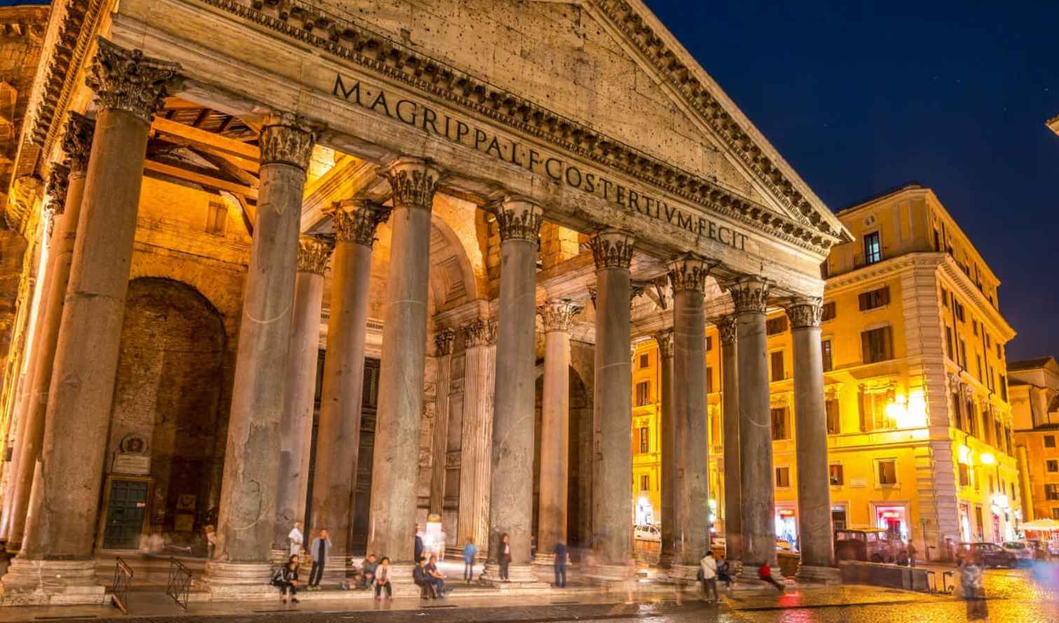 Pantheon in Rome illuminated at night with people in front.