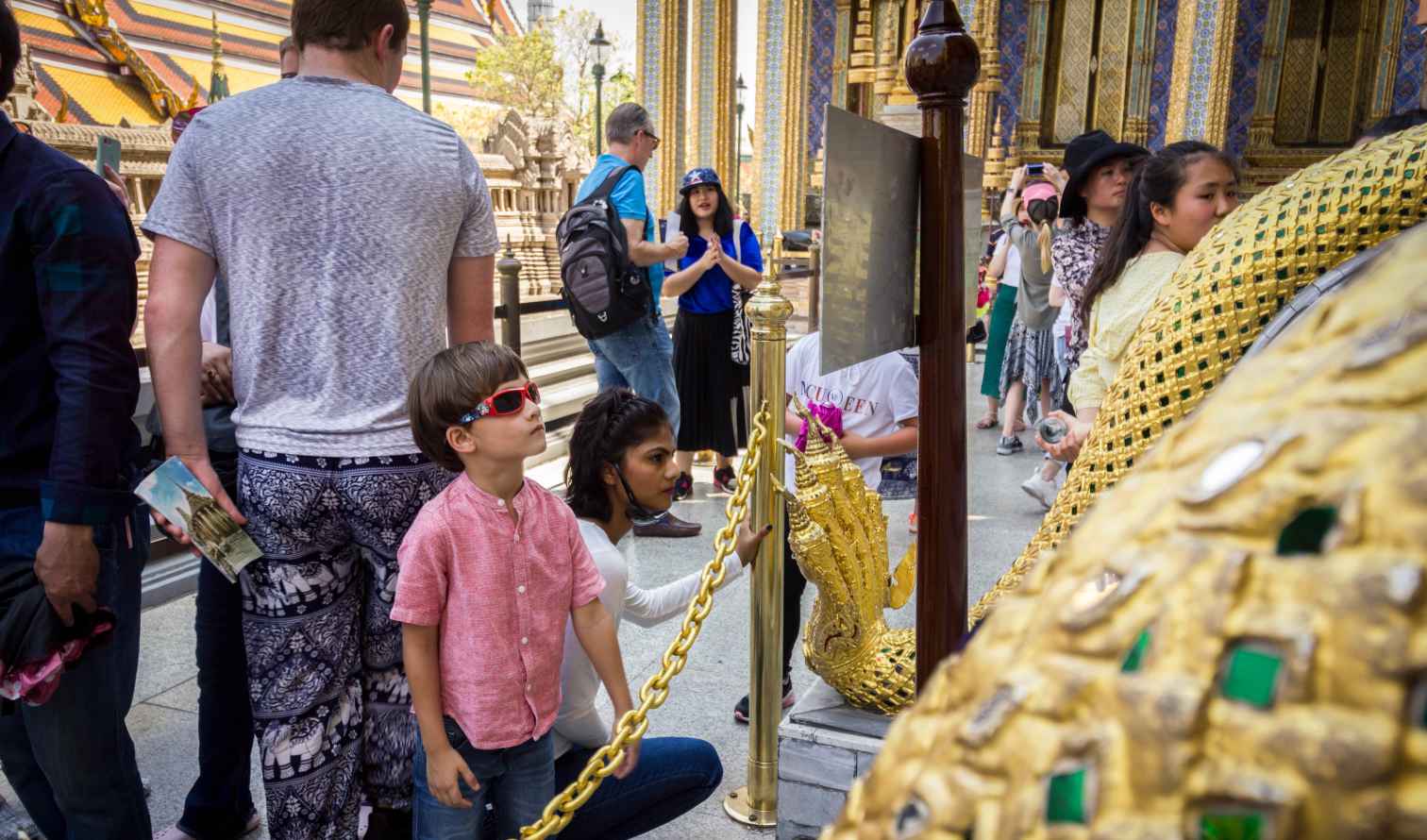 Visitors observing golden sculptures at Wat Phra Kaew, Bangkok.