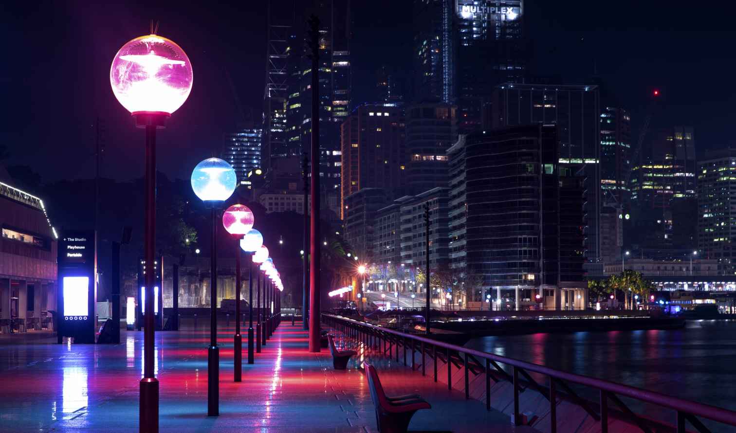 Empty benches along the vibrantly lit walkway at Circular Quay, Sydney.