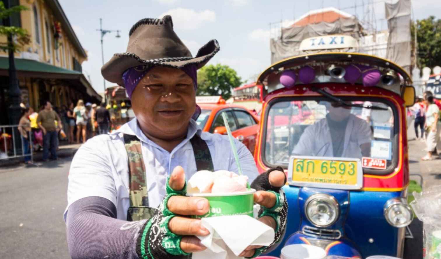 Street vendor in Bangkok offering ice cream in front of a tuk-tuk.