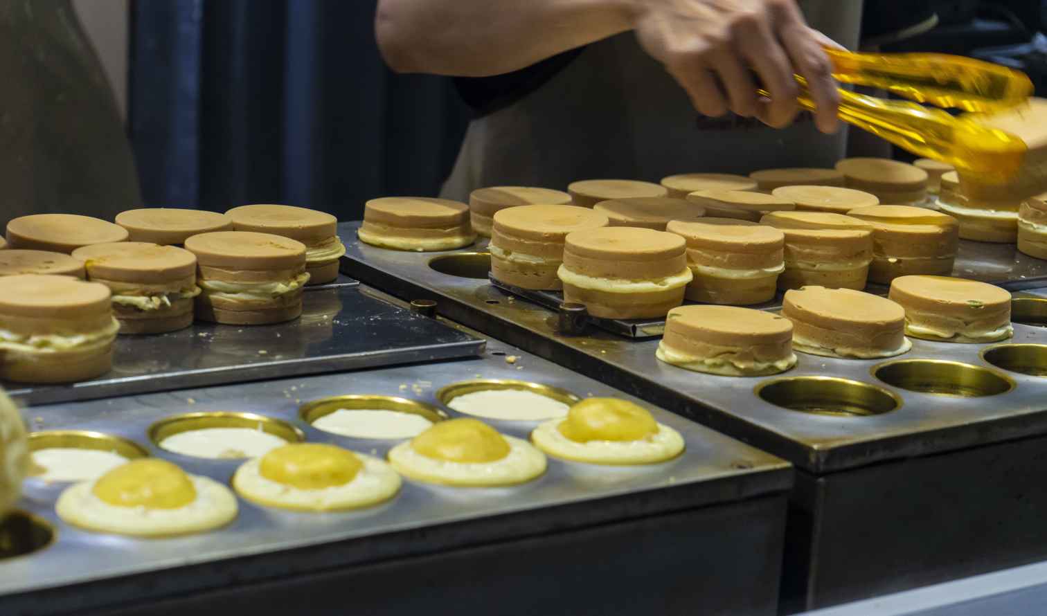 Person using tongs to prepare  pancake pastries on a griddle in Taipei