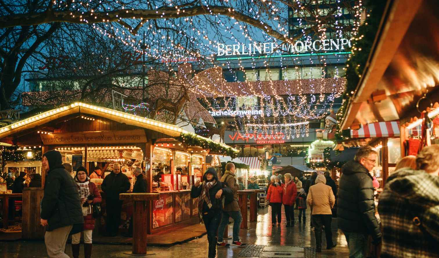 People walking at a Christmas market in Berlin at night.