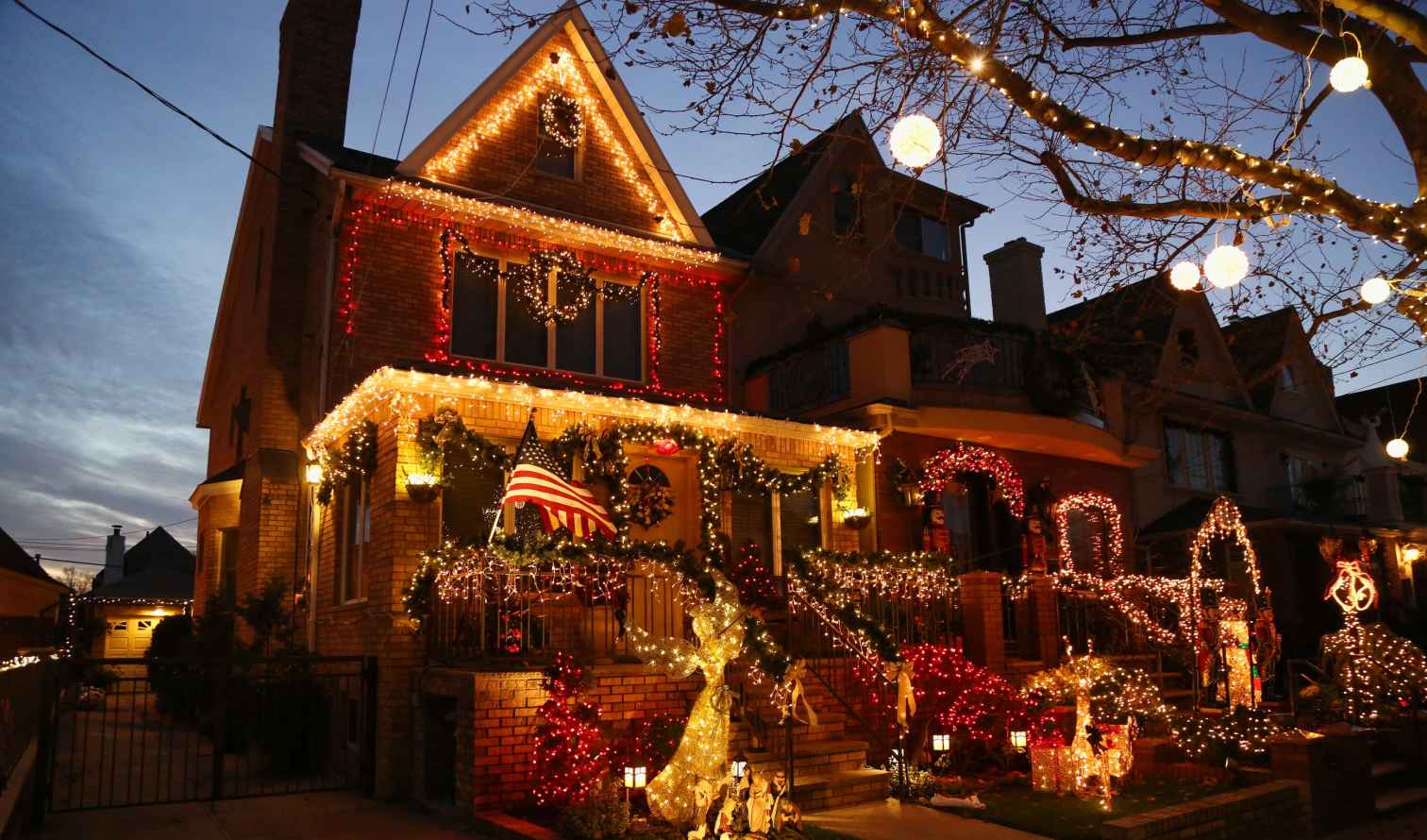 American flag displayed on a house with elaborate holiday lights in Brooklyn.