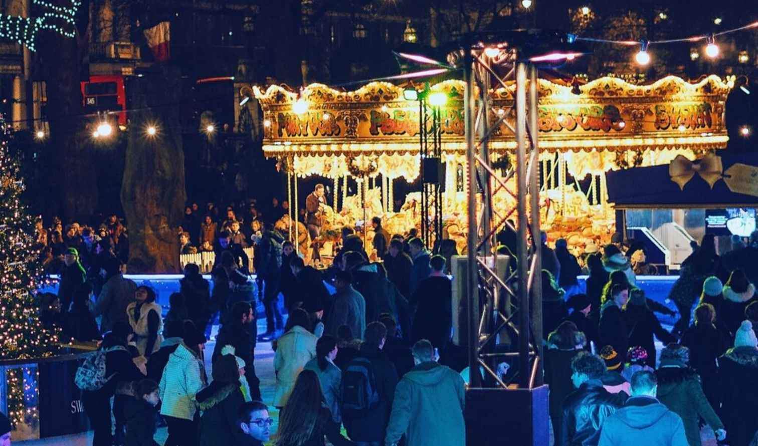 Ice skating at a rink near a large decorated Christmas tree in London