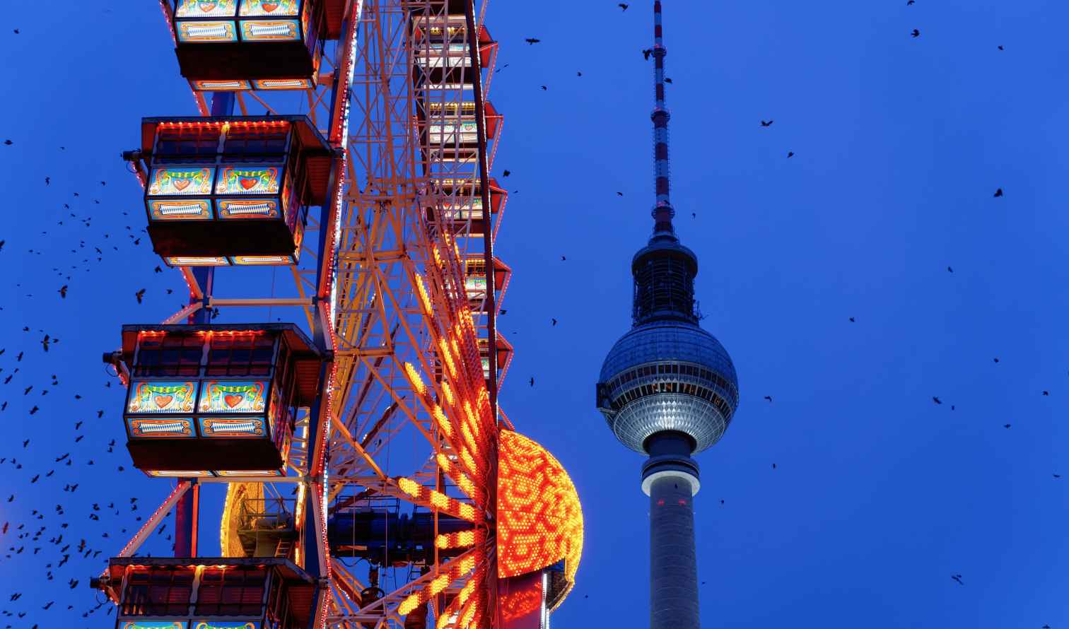 Ferris wheel near the Berlin TV Tower against a blue sky.