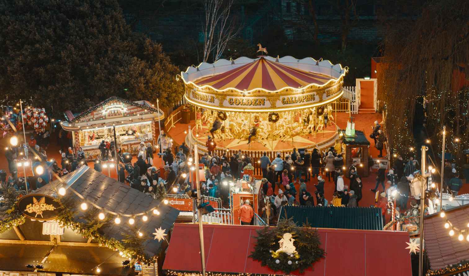 People gather around a Victorian carousel at a Christmas market during the evening in Edinburgh