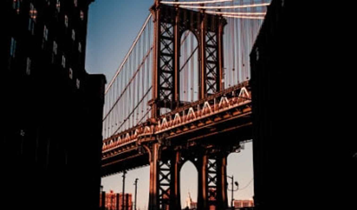 View of the Manhattan Bridge framed by two buildings in Brooklyn.