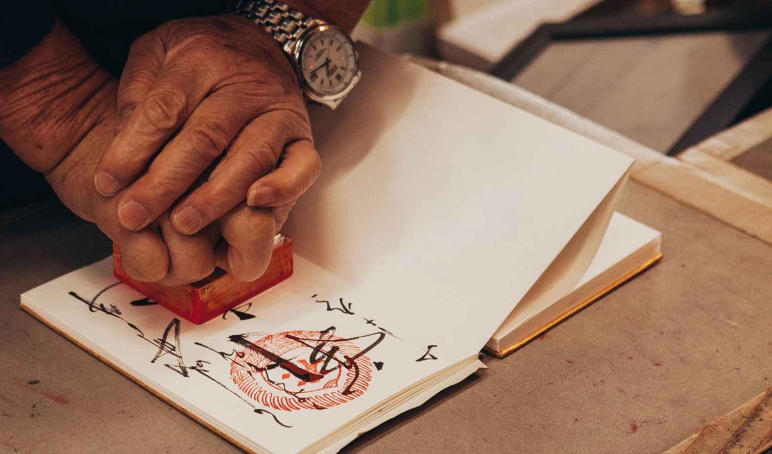 Person stamping a book with a red seal on a table Nara