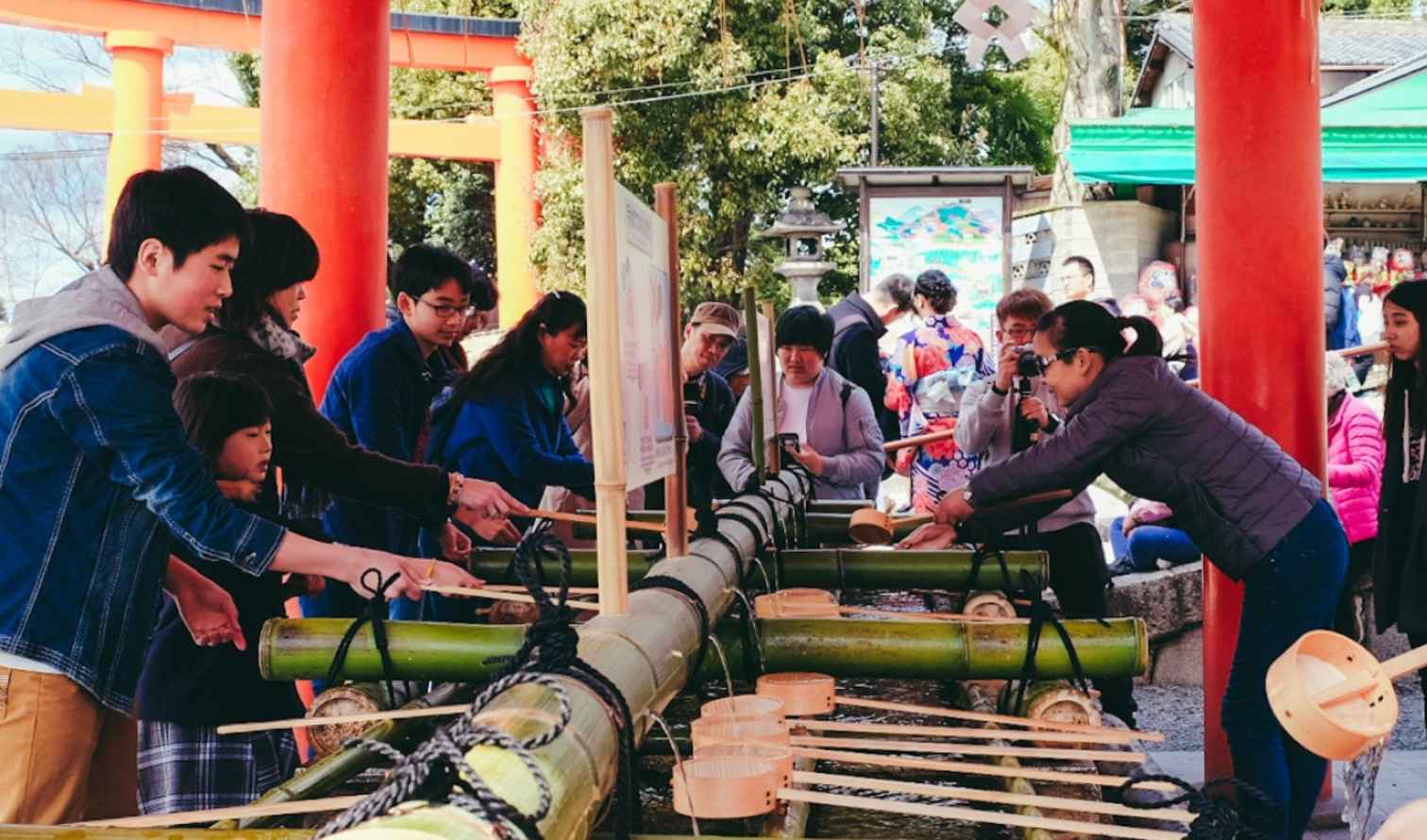 People using water ladles at a purification fountain in Kyoto, Japan.