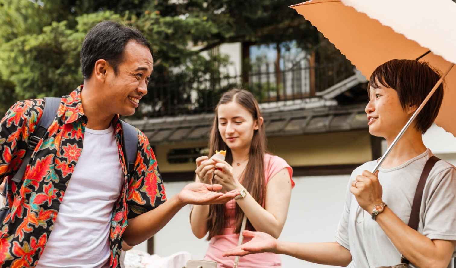 Group of people standing outdoors in a residential area with a large tree in Osaka