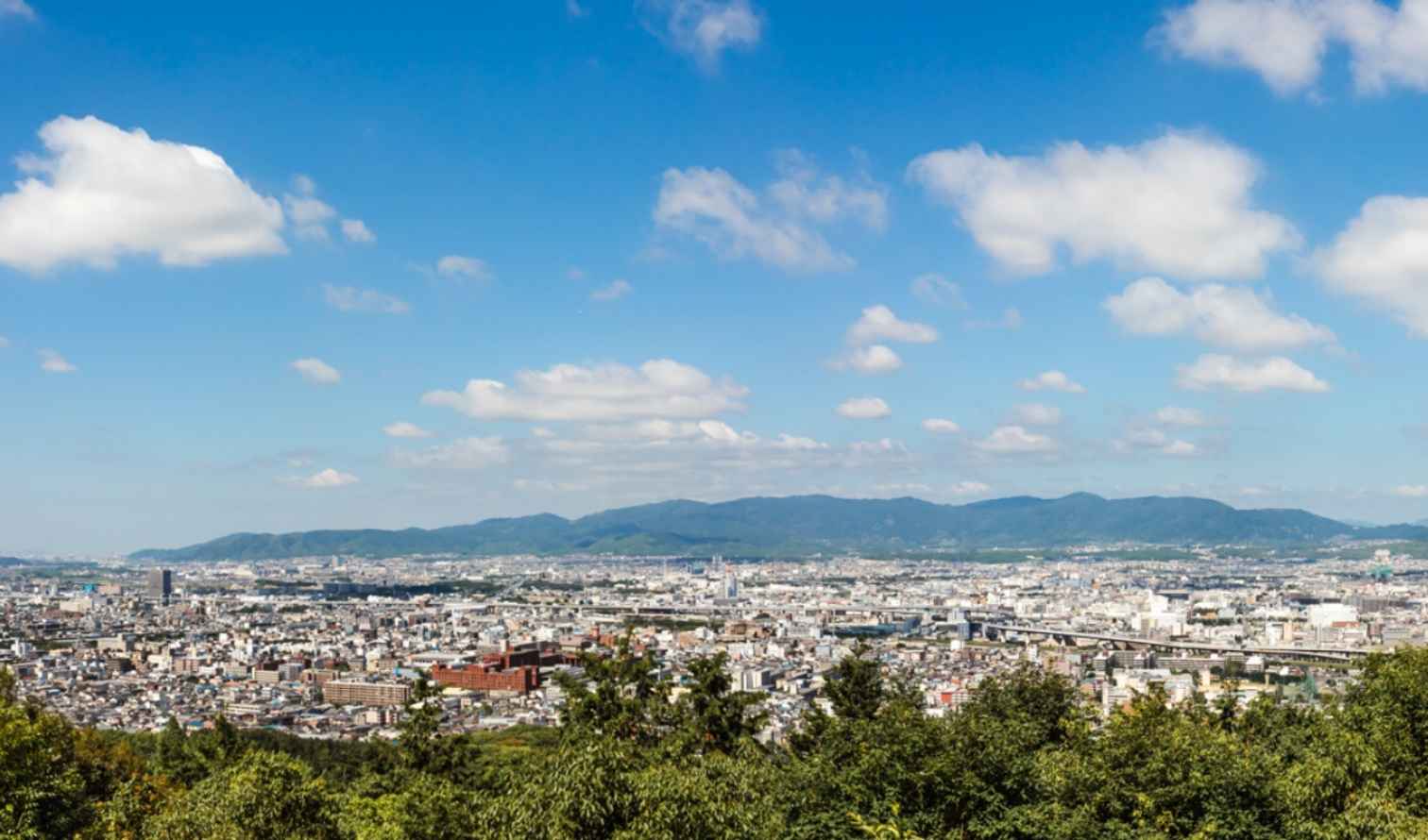 Aerial view of Osaka cityscape with mountains in the background.