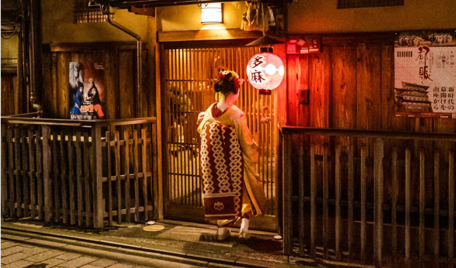 A geisha entering a traditional wooden building in Gion, Kyoto.