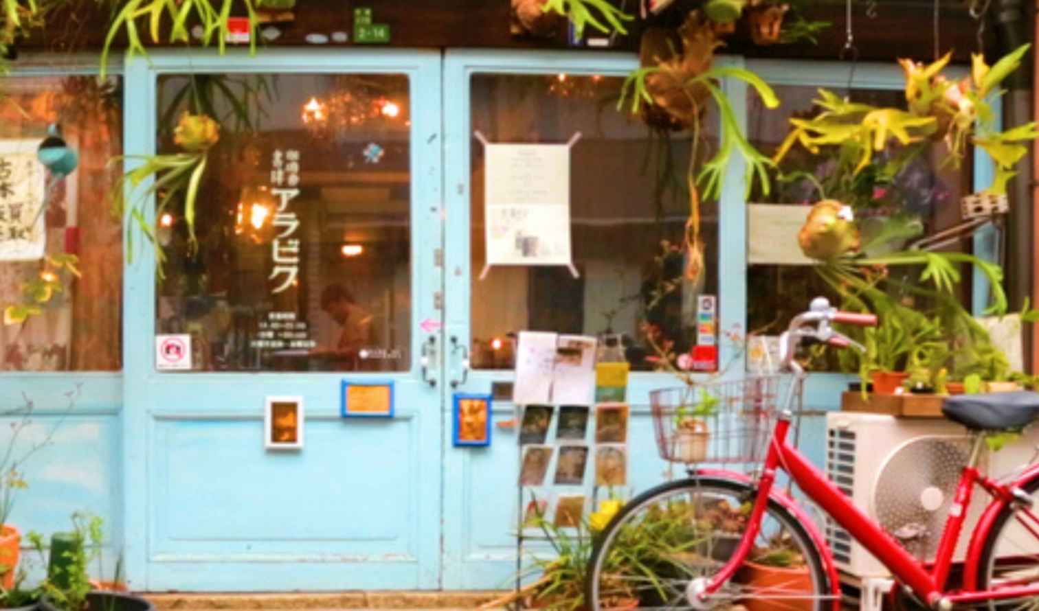 Red bicycle in front of a shop with hanging plants in Osaka
