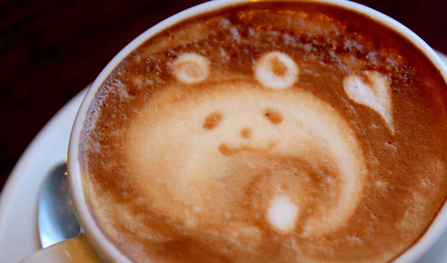 Latte art depicting a bear face with a heart in a cup of coffee in Osaka