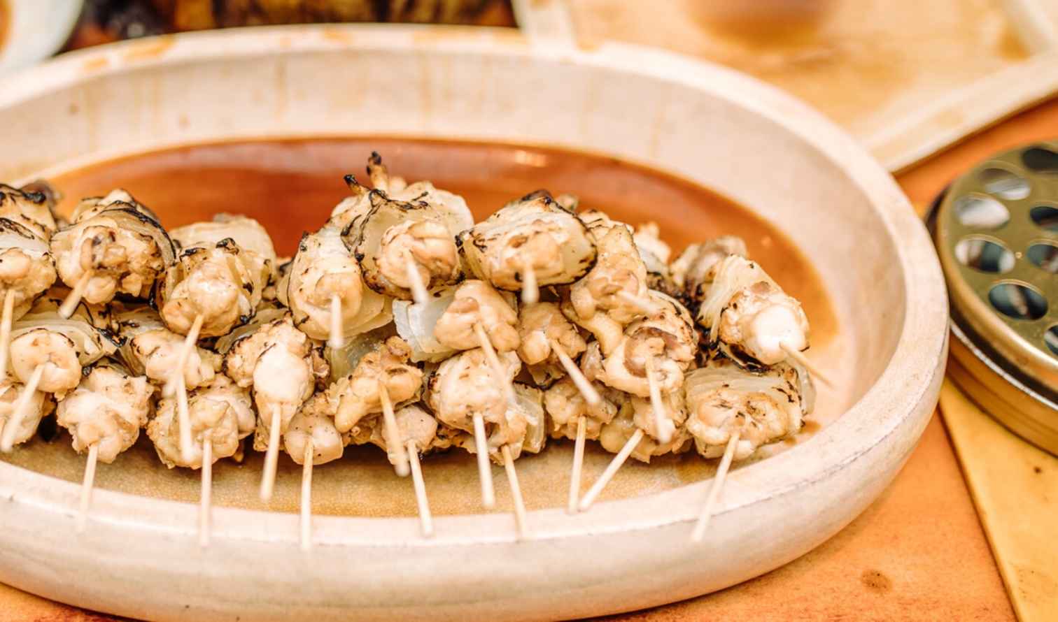 Grilled skewers arranged on a round plate on a wooden table in Osaka