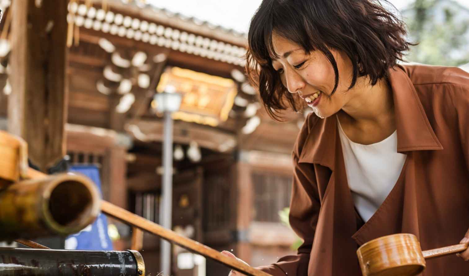 Person using a wooden ladle at a Japanese shrine water basin Osaka