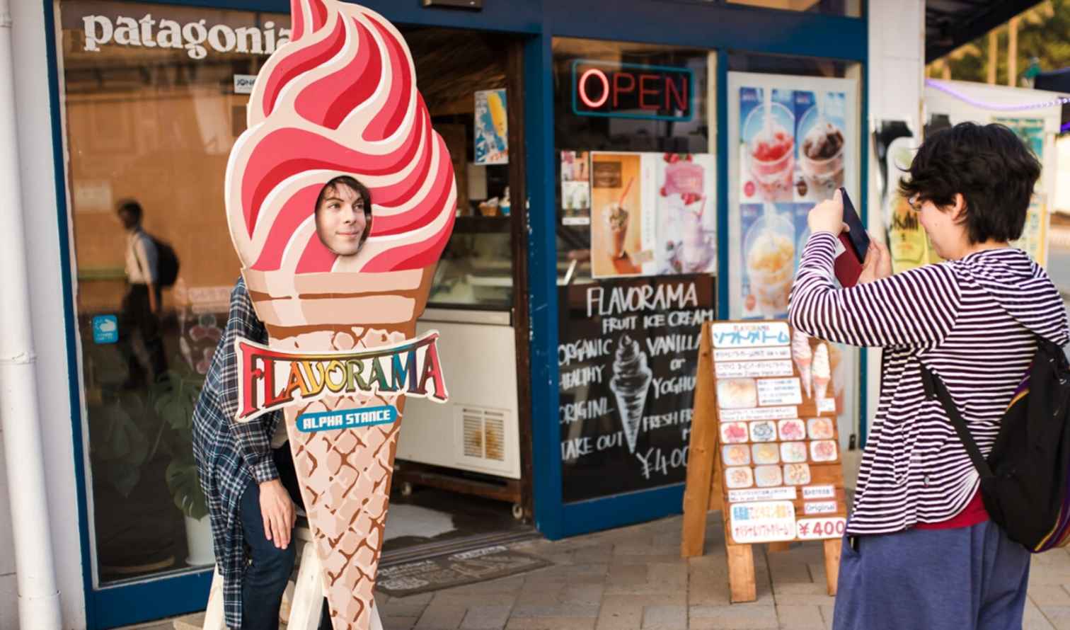 Person posing in a Flavorama ice cream cone cutout outside a shop in Fukuoka