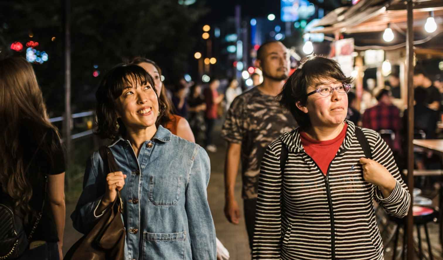 People walking through a night market street with food stalls in Fukuoka