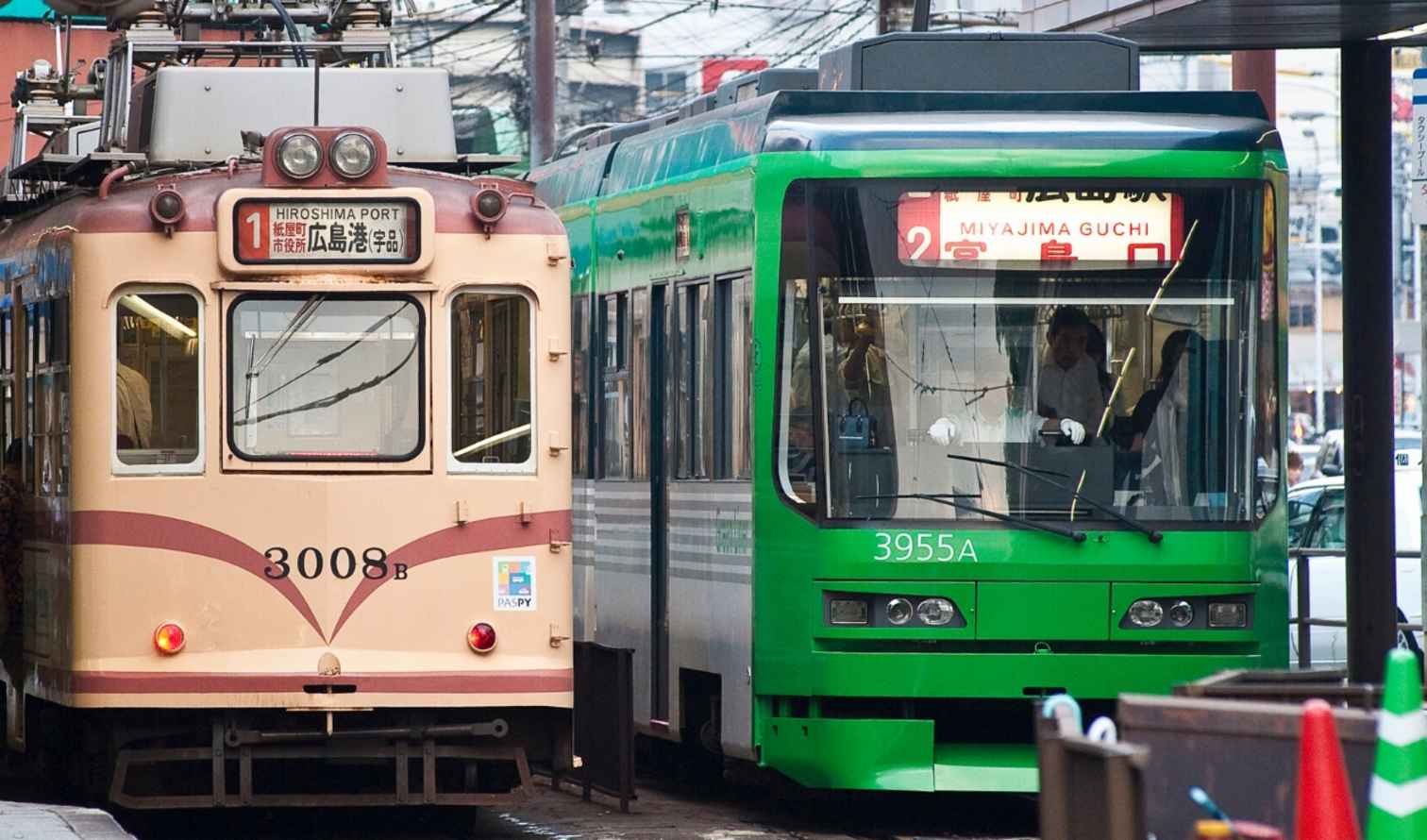 Two trams, one beige and one green, in Hiroshima, Japan.