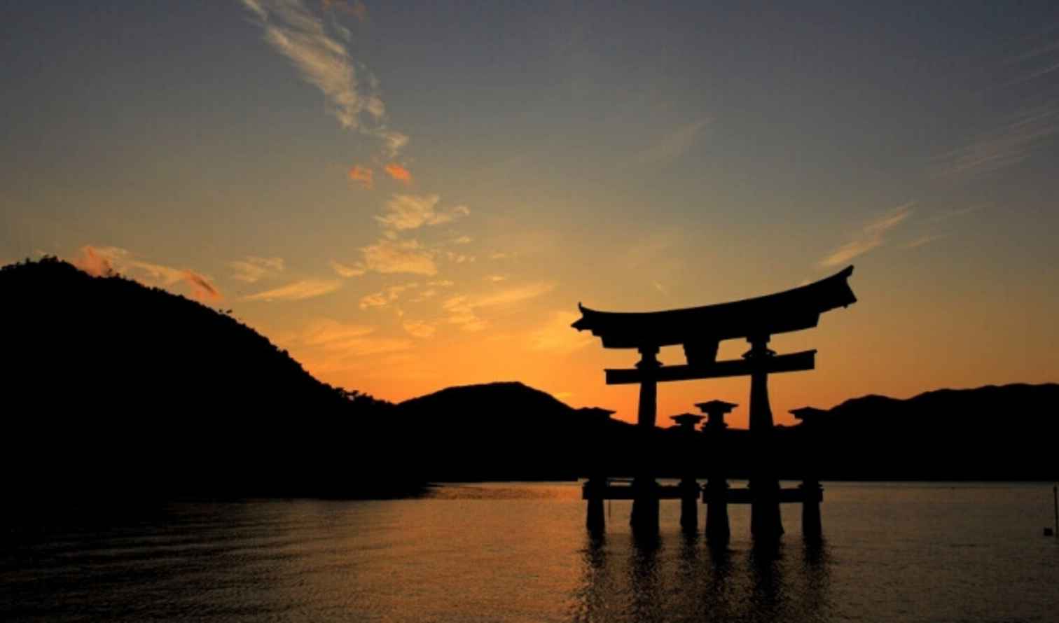 Torii gate at Itsukushima Shrine silhouetted against the sunset.