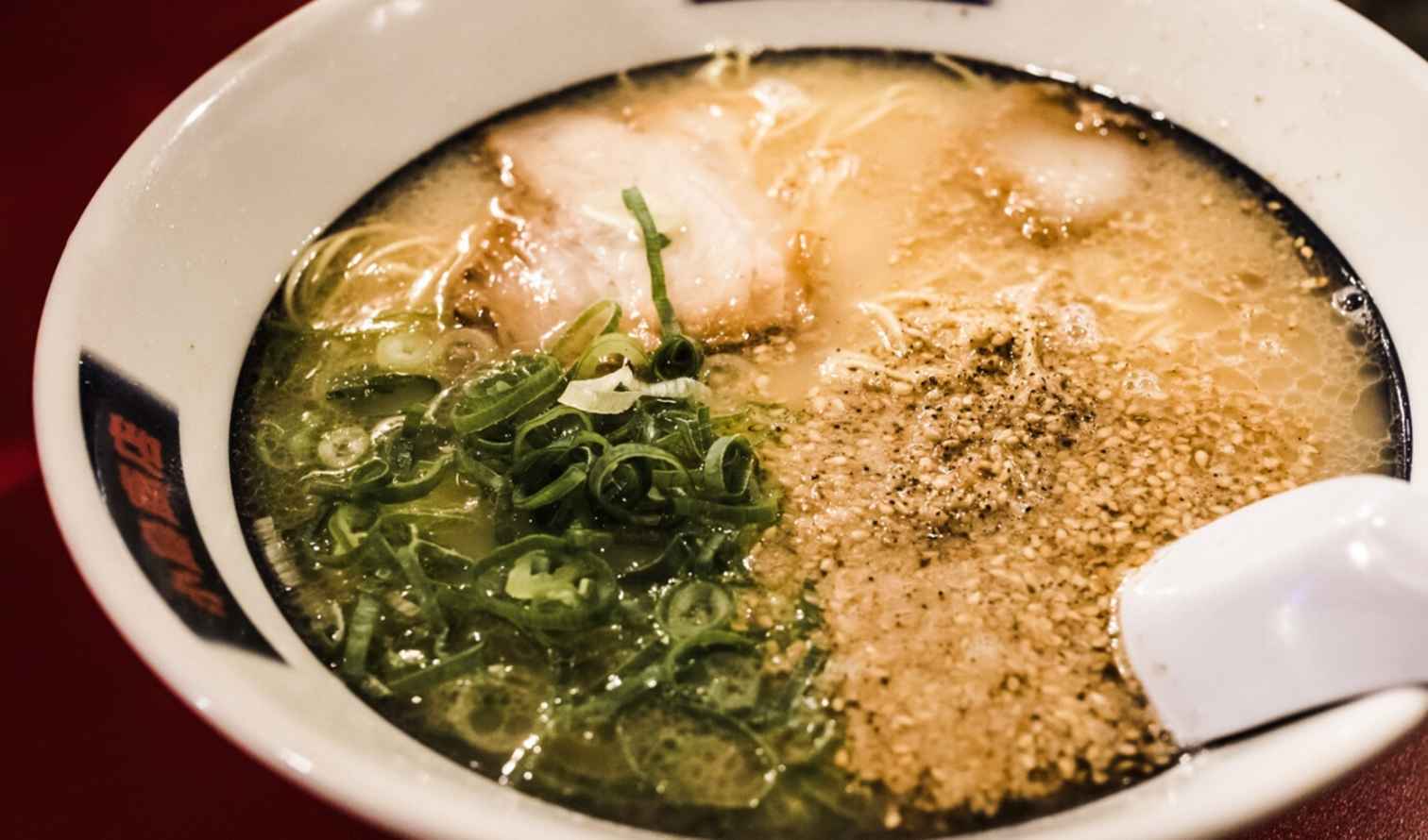 Close-up of a bowl of ramen with green onions and sesame seeds in Fukuoka