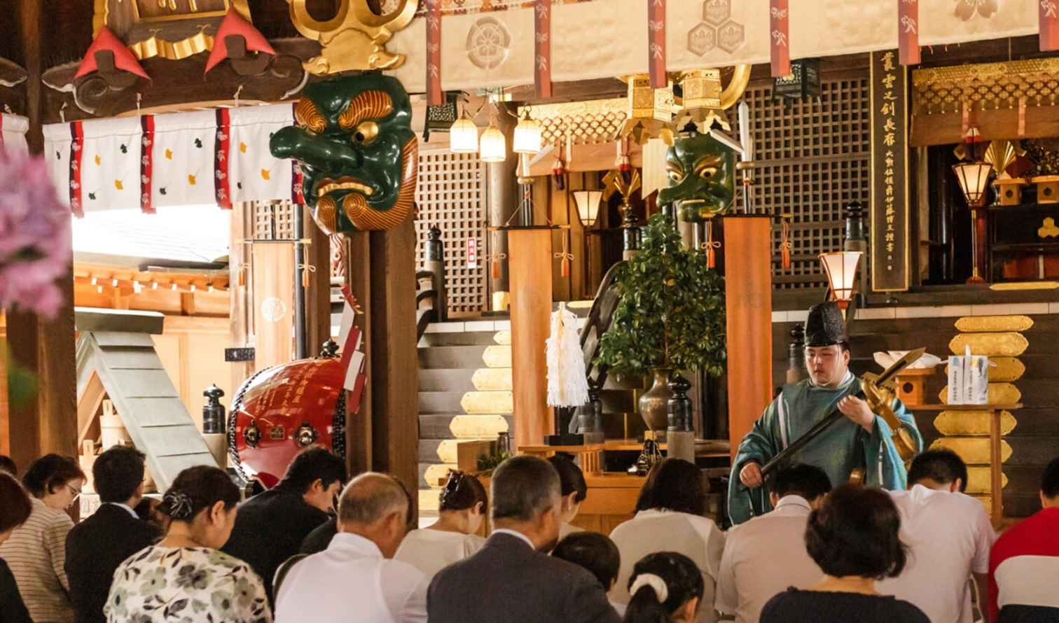 Interior view of Yasaka Shrine, featuring decorative masks and attendees.