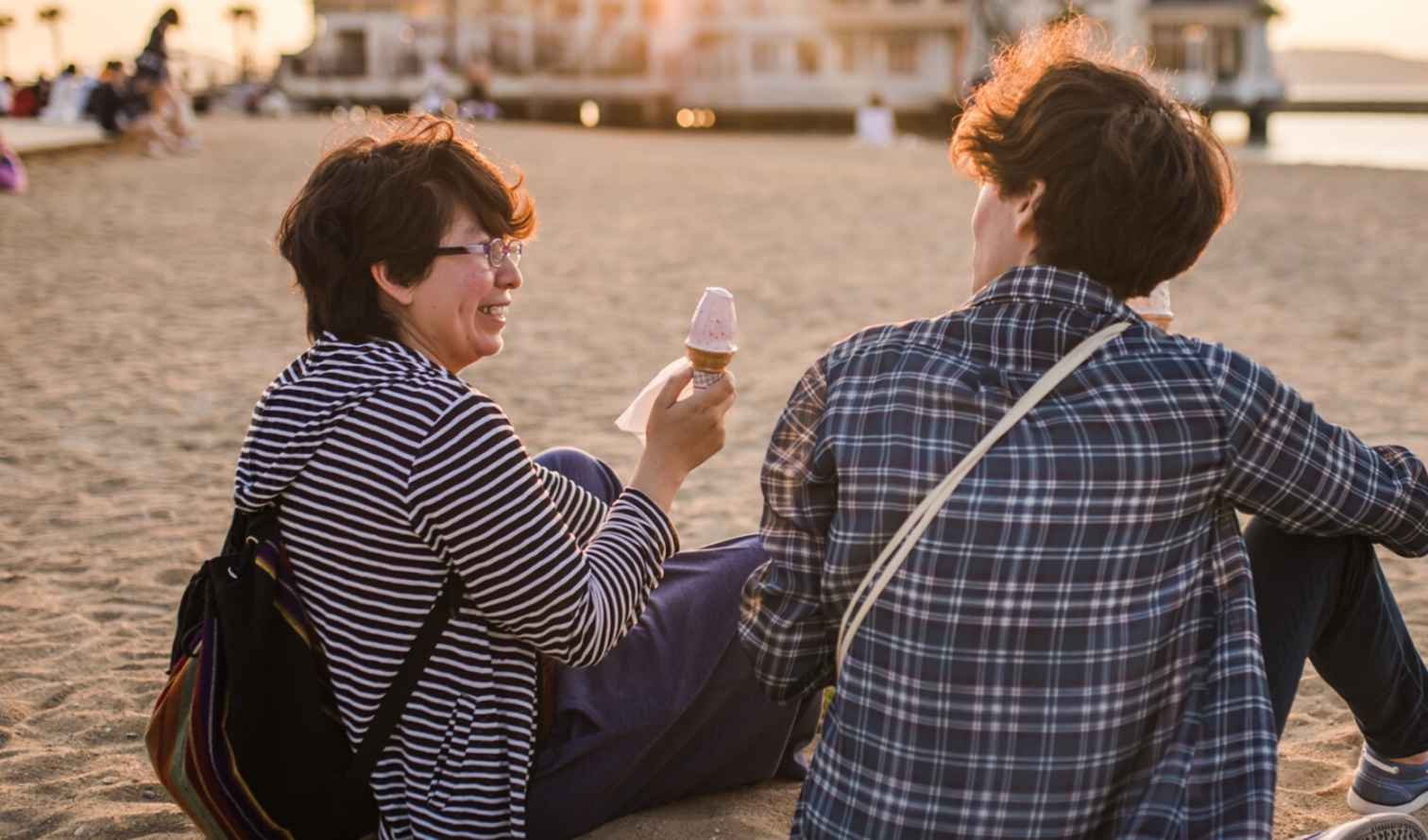 Two people sitting on a sandy beach with ice cream in Fukuoka