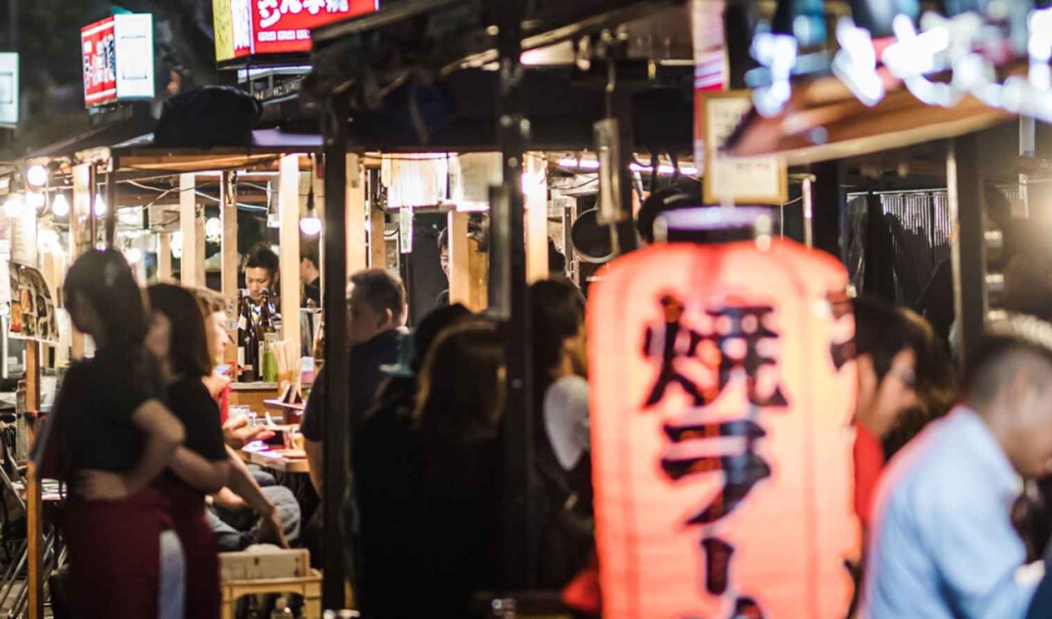 Street food stalls in Fukuoka, Japan at night with people dining.