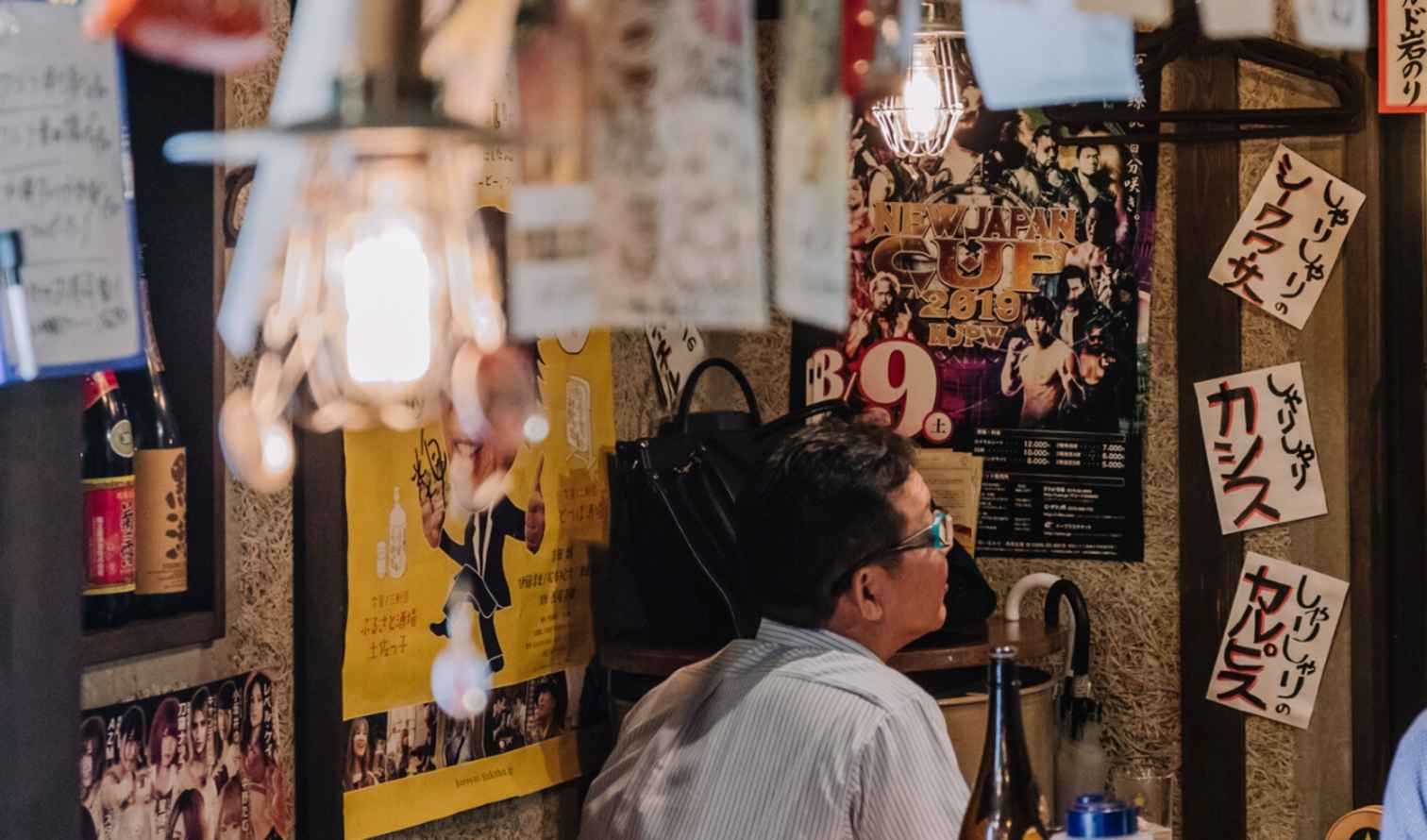 Interior of a Japanese izakaya with hanging paper menus and posters in Nagoya