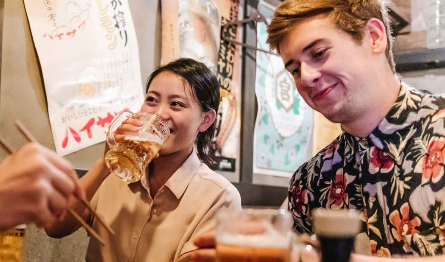 People enjoying drinks in a Japanese izakaya restaurant with posters on the walls in Nagoya