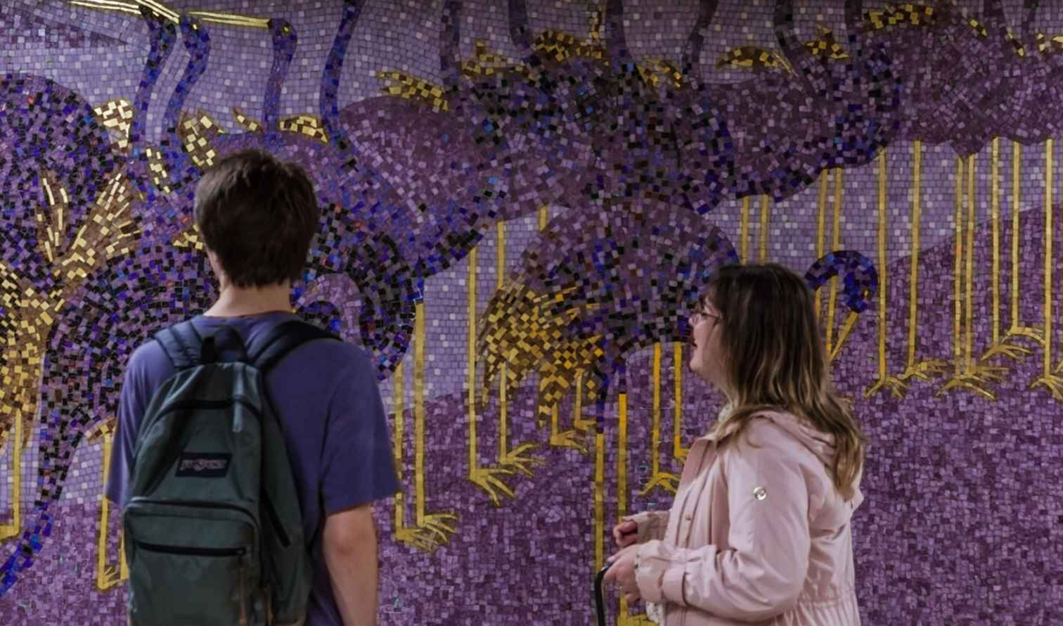 Two people observing a mosaic mural in a public space in Nagoya